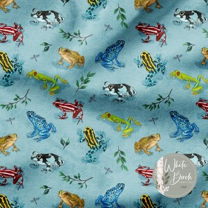 May include: Light blue fabric with a repeating pattern of colorful frogs, dragonflies, and sprigs of leaves. The frogs are in various colors, including red, yellow, blue, green, and black and white. The fabric has a watercolor effect.
