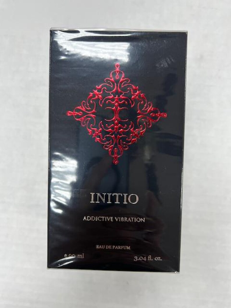 Puede incluir: Una botella negra de Initio Addictive Vibration Eau de Parfum. La botella tiene un dise&ntilde;o rojo y dorado con el nombre de la marca y el nombre de la fragancia impresos en la parte delantera. La botella es de 90 ml.