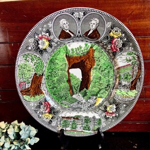 May include: A vintage ceramic plate with a colorful design featuring the Natural Bridge of Virginia. The plate depicts the bridge, surrounding foliage, and historical figures. It also includes the text "Natural Bridge of Virginia" and "Natural Bridge Hotel".