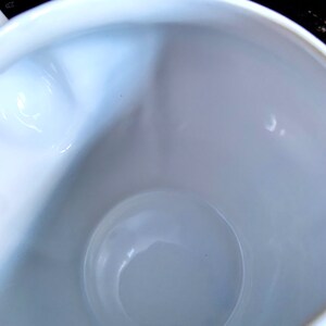 Pu&ograve; includere: Una tazza in ceramica bianca con una finitura liscia e lucida. L'interno della tazza &egrave; vuoto.