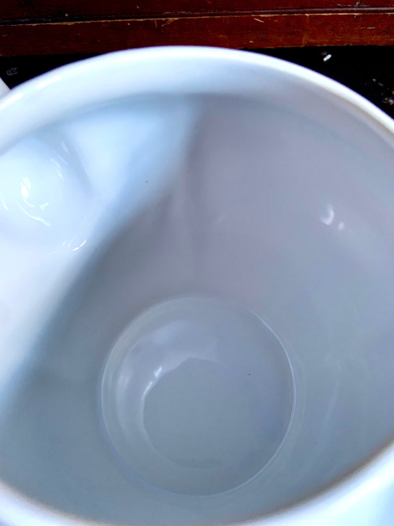 Pu&ograve; includere: Una tazza in ceramica bianca con una finitura liscia e lucida. L'interno della tazza &egrave; vuoto.