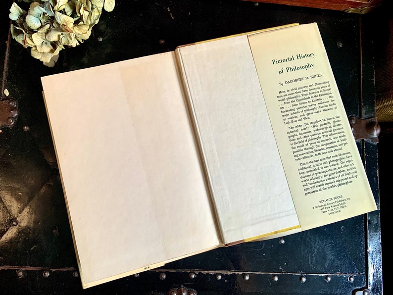 Puede incluir: Un libro cerrado con una cubierta blanca y un lomo amarillo. La contraportada tiene un texto que dice "Pictorial History of Philosophy by  Dagobert D. Runes".