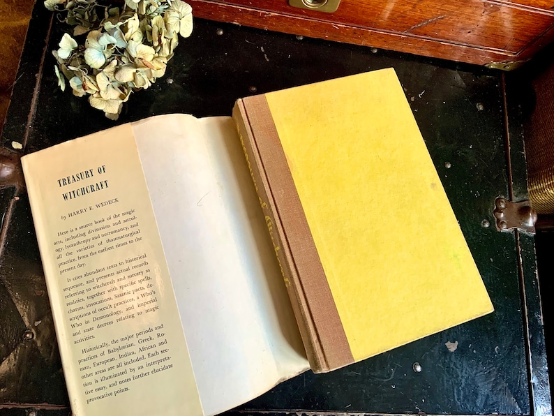 Puede incluir: Un libro de tapa dura amarillo titulado "Treasury of Witchcraft" de Harry E. Wedeck. El libro est&aacute; abierto en la primera p&aacute;gina, revelando texto sobre la historia y la pr&aacute;ctica de la brujer&iacute;a.
