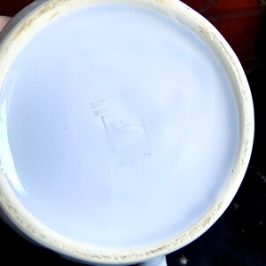 Pu&ograve; includere: Teiera in ceramica bianca con una glassa blu chiaro. Il fondo della teiera ha un piccolo timbro rettangolare sbiadito.