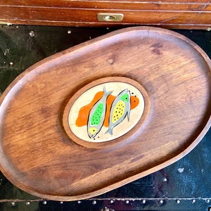 May include: A wooden serving tray with a removable oval insert featuring two stylized fish with green, yellow, and orange details on a white background.