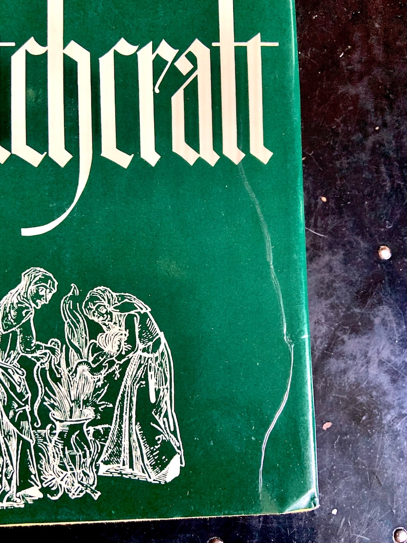 Puede incluir: Un libro verde con la palabra "Witchcraft" impresa en blanco en la portada. La portada tambi&eacute;n presenta una ilustraci&oacute;n en blanco y negro de tres personas de pie alrededor de un caldero.