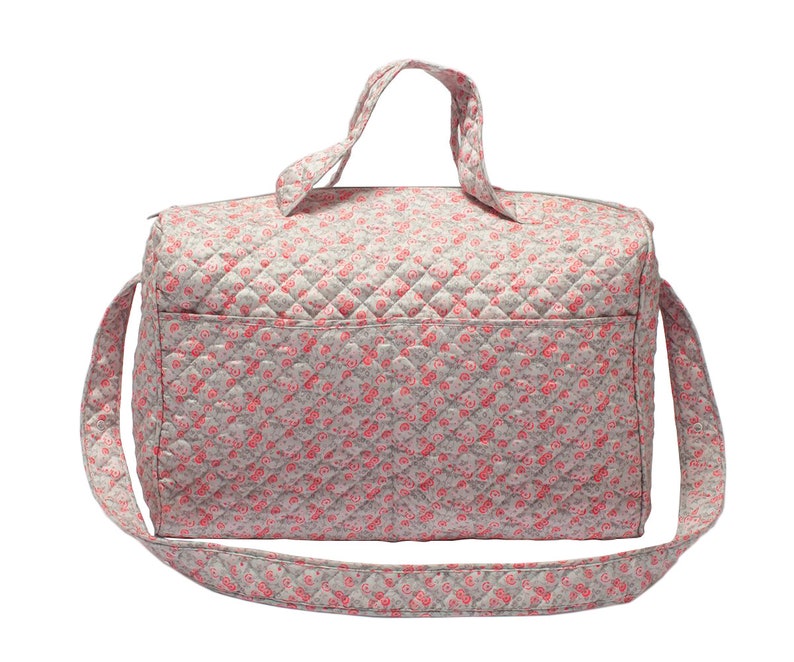 K&ouml;nnte beinhalten: Eine graue gesteppte Reisetasche mit einem rosa floralen Muster und einem langen Schultergurt.