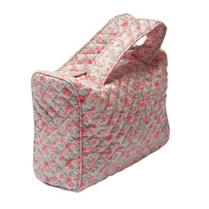 K&ouml;nnte beinhalten: Eine gesteppte Kosmetiktasche mit floralem Muster in Rosa und Wei&szlig; und einem oberen Tragegriff.
