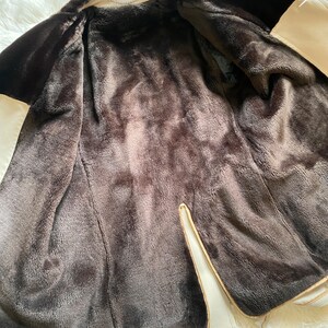 May include: A cream-colored faux fur jacket with a brown faux fur lining. The jacket is unzipped and the lining is visible.
