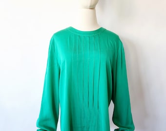 May include: A green long-sleeved blouse with a round neckline and vertical pleats down the front.