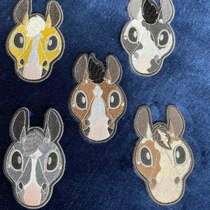 May include: Five embroidered horse head patches in different colors and patterns. The patches are on a dark blue background.