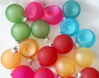 Op de afbeelding: Een verzameling van 17 kleurrijke glazen kerstballen in verschillende tinten rood, roze, oranje, geel, groen, blauw en turquoise. De ballen zijn rond en hebben een matte afwerking.