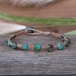 May include: A turquoise and brown beaded bracelet with a knotted cord.