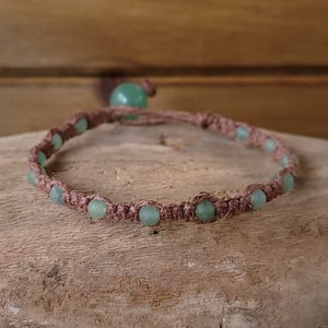 May include: A brown cord bracelet with light green stone beads.