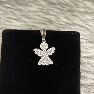 Op de afbeelding: Een zilveren engelhanger met heldere kristallen accenten. De hanger ligt op een zwarte fluwelen achtergrond.
