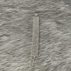 Puede incluir: Un brazalete plateado con un dise&ntilde;o de cadena hecho de peque&ntilde;os diamantes de imitaci&oacute;n transparentes.
