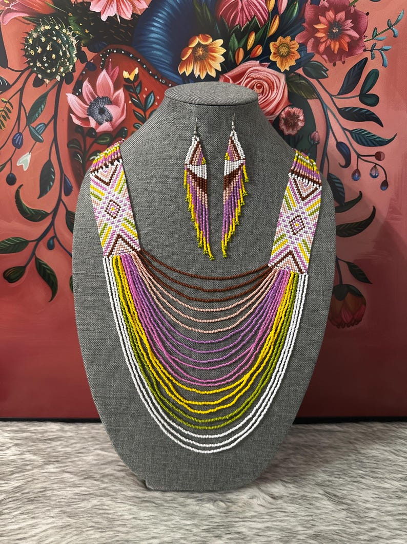 Op de afbeelding: Een meerrijige kralenketting met een geometrisch patroon in wit, roze, geel en groen. De ketting wordt geleverd met bijpassende oorbellen.