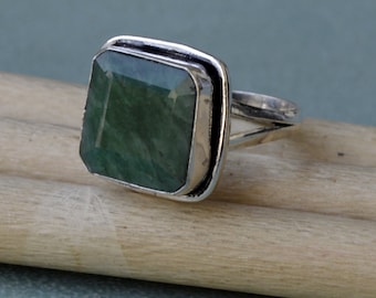 Puede incluir: Un anillo de plata con una piedra preciosa verde cuadrada engastada en un engaste de bisel.