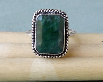 Puede incluir: Un anillo de plata con una gran piedra preciosa rectangular verde engastada en un borde de cuerda.