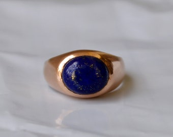 May include: A rose gold ring with a blue lapis lazuli gemstone.
