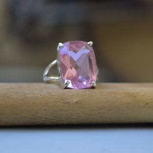 May include: A silver ring with a large, rectangular, light pink gemstone.