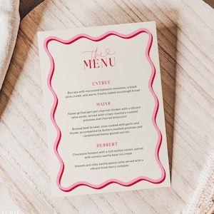 May include: A menu card with a pink wavy border and the words "The Menu" at the top. The menu lists entree, mains, and dessert options. The card is on a wooden charger with a linen napkin and dried floral accents.