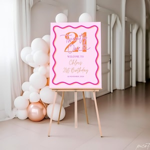 May include: Pink welcome sign with a wavy border in orange and pink. The sign says "Twenty One" in orange and pink with a script font "Welcome to Chloe's 21st Birthday 20 November 2024".
