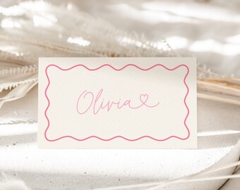 May include: A white card with a pink border and the name "Olivia" written in pink cursive with a small pink heart next to it.