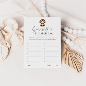 May include: A printable baby shower game card with a monkey illustration. The card has the title "Guess what's in the diaper bag" and instructions to write down the items you think are in the diaper bag. The person with the most correct answers wins.