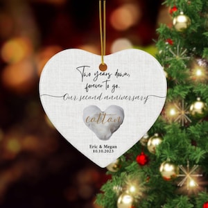 May include: White heart-shaped ceramic ornament with the text "Two years down, forever to go. Our second anniversary cotton" and the names "Eric & Megan" and the date "10.10.2023".
