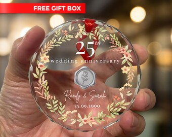 Könnte beinhalten: Ein klarer, facettierter Glasornament mit dem Text "25. Hochzeitstag" und floralen Akzenten. Der Ornament enthält die Namen "Randy & Sarah" und das Datum "25.09.2000". Ein rotes Band ist zum Aufhängen befestigt.