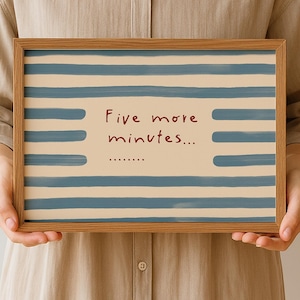 Può includere: Una stampa incorniciata con una cornice in legno chiaro. La stampa presenta strisce orizzontali blu su sfondo crema. Il testo "Five more minutes..." è scritto in rosso.