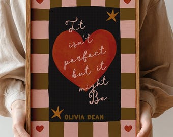 Può includere: Una stampa artistica incorniciata con la citazione "It isn't perfect but it might be" e un design a cuore rosso. L'opera d'arte ha uno sfondo nero con un cuore rosso, stelle dorate e un bordo a scacchi rosa e marrone. Il nome dell'artista, Olivia Dean, è in basso.