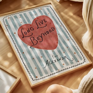 May include: Framed art print with a wooden frame. The artwork features a red heart with the words "Long Live Boyhood" and the name "Alexandr" below. The background has blue and white stripes with small star accents.