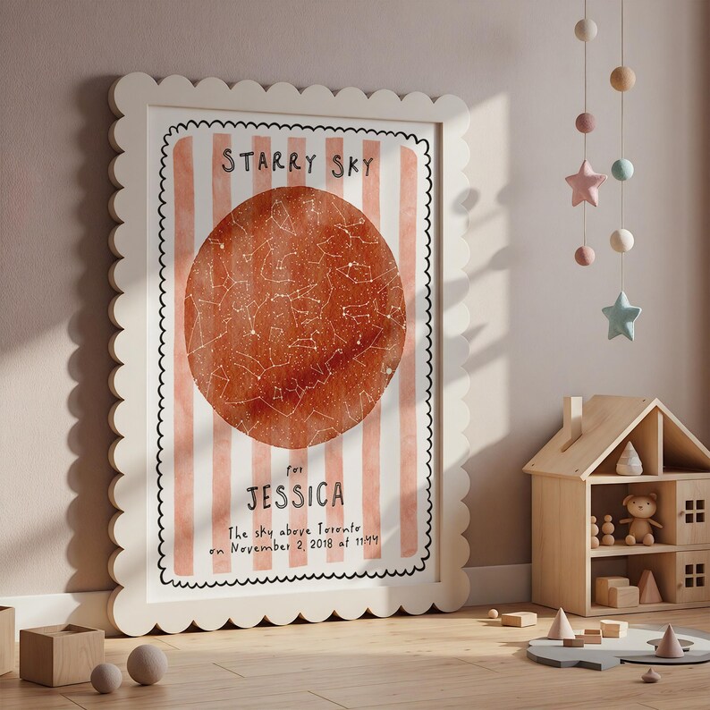 May include: A framed print with a scalloped edge features a watercolor-style starry sky map in shades of orange and white. The text "Starry Sky" is at the top, with the name "Jessica" and date below. The print is in a white frame.