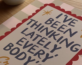 Puede incluir: Una tarjeta de felicitación con el texto "I've been thinking lately every body's crazy" en azul marino. La tarjeta tiene un borde festoneado rojo y un patrón de cuadros rosa claro y beige. Una taza blanca está en la esquina superior izquierda.