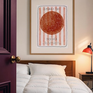 May include: A framed print with a starry sky design. The print features a red circle with constellations, set against a background of vertical pink and white stripes. Text reads "Starry Sky for Jessica". The print is in a wooden frame.