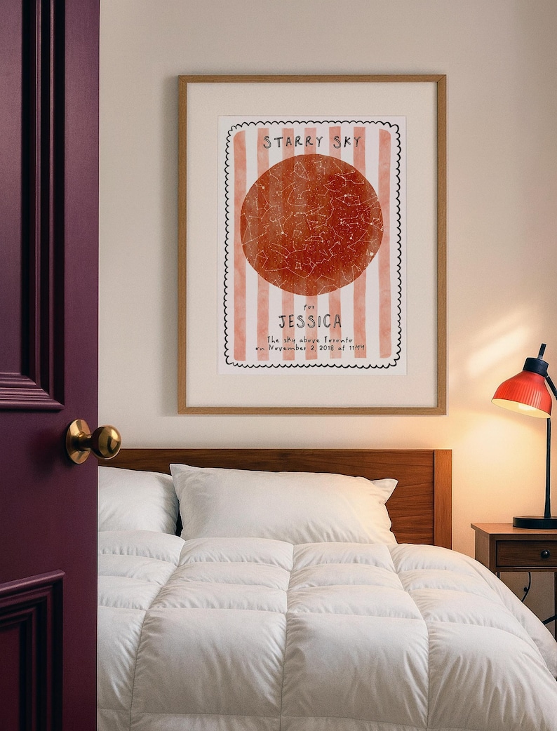 May include: A framed print with a starry sky design. The print features a red circle with constellations, set against a background of vertical pink and white stripes. Text reads "Starry Sky for Jessica". The print is in a wooden frame.