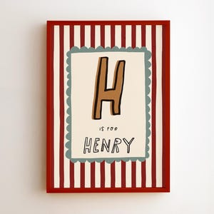 Op de afbeelding: Een ingelijste kunstafdruk met een rode rand. Het kunstwerk heeft een crèmekleurige achtergrond met een bruine letter "H" en de tekst "IS FOR HENRY". De achtergrond heeft verticale rood-witte strepen.
