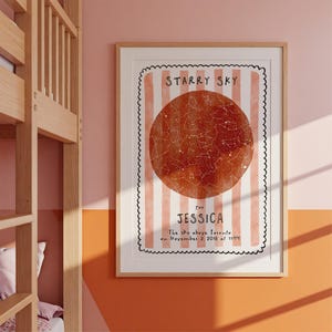 May include: A framed print featuring a star map with a red-orange circular design. The print has a white border with a black scalloped edge and vertical pink stripes. Text reads "STARRY SKY" and "for JESSICA". Below, it says "The sky above Toronto on November 2, 2018 at 11:44".