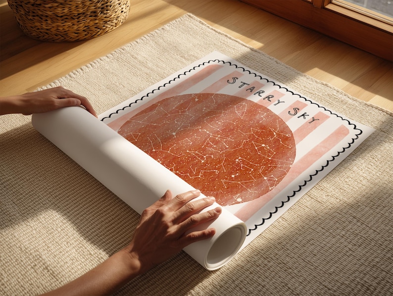 May include: A rolled-up poster with a celestial map design is being unrolled. The poster features a large, reddish-brown circle with constellations and the words "Starry Sky" in black. The background has pink stripes.