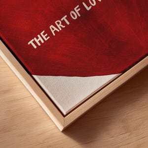 May include: A framed canvas print with the text "THE ART OF LOVE" in white against a red background. The bottom portion of the canvas is white. The frame is made of light-colored wood.
