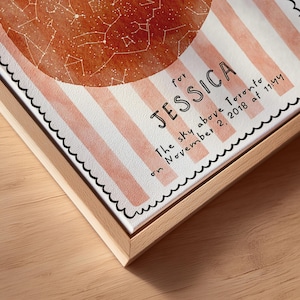 May include: A framed canvas print featuring a watercolor-style celestial map in shades of orange and white. The print includes the name "JESSICA" and the text "The sky above Toronto on November 2, 2018 at 11:44". The frame is made of light-colored wood.