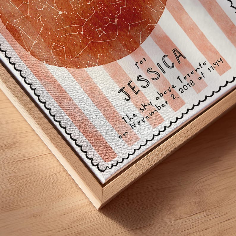 May include: A framed canvas print featuring a watercolor-style celestial map in shades of orange and white. The print includes the name "JESSICA" and the text "The sky above Toronto on November 2, 2018 at 11:44". The frame is made of light-colored wood.