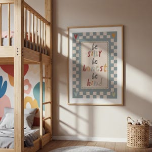 Pode incluir: Uma impress&atilde;o emoldurada com as palavras "be silly, be honest, be kind" em letras coloridas. A impress&atilde;o tem uma borda xadrez azul claro e branco com detalhes de cora&ccedil;&atilde;o. A impress&atilde;o est&aacute; em uma moldura de madeira clara.