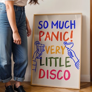Könnte beinhalten: Ein gerahmter Kunstdruck mit dem Text "SO MUCH PANIC! VERY LITTLE DISCO" in Blau, Rot, Gelb, Grün und Pink. Das Kunstwerk enthält Strichzeichnungen von Händen, die Cocktails halten. Der Rahmen ist hellholzfarben.