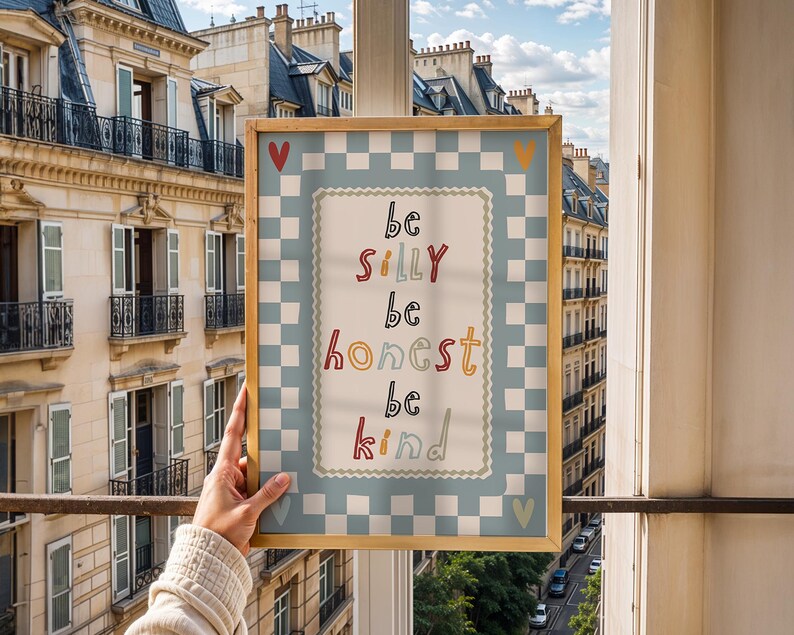 Pode incluir: Uma impress&atilde;o emoldurada com as palavras "be silly be honest be kind" em letras coloridas. A impress&atilde;o tem uma borda xadrez azul claro e branco e uma moldura dourada. Cora&ccedil;&otilde;es vermelhos e amarelos est&atilde;o nos cantos.