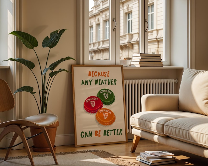 May include: A framed poster with the text "BECAUSE ANY WEATHER CAN BE BETTER" and three Guinness bottle cap designs in red, green, and orange. The poster is in a living room setting with a plant, chair, and sofa.