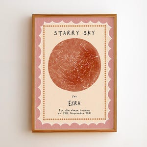 May include: A rectangular framed print featuring a circular terracotta-colored star map with white constellations. The cream-colored background has a scalloped pink border with orange dots. Text reads: STARRY SKY for EZRA The sky above London on 29th November 2021.