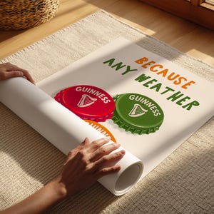 May include: A rolled-up poster featuring a red and green Guinness bottle cap design with the text "BECAUSE ANY WEATHER". The poster is on a beige rug, with a wicker basket in the background.
